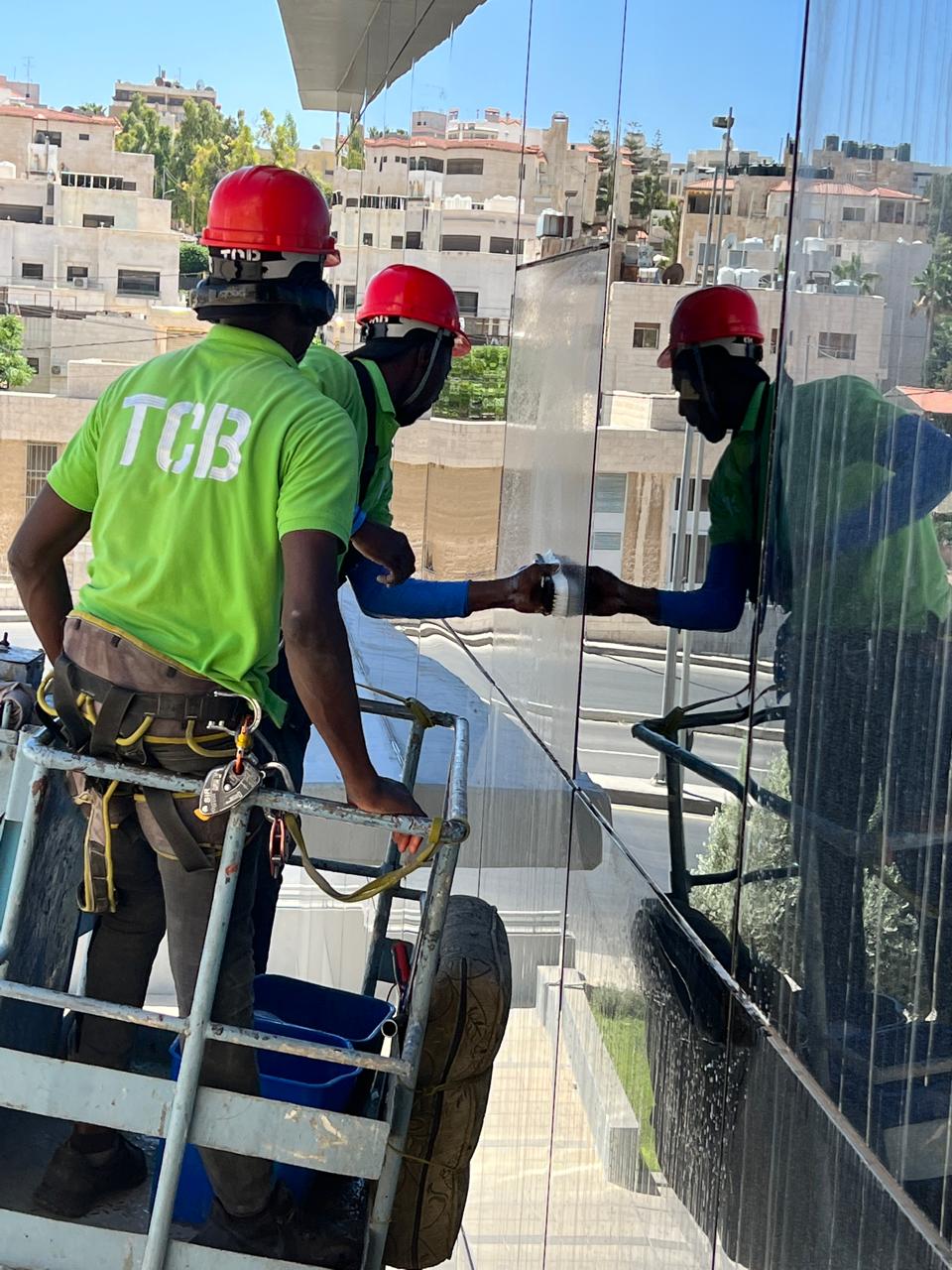 عامل ينظف واجهة زجاجية بتقنية الحبال