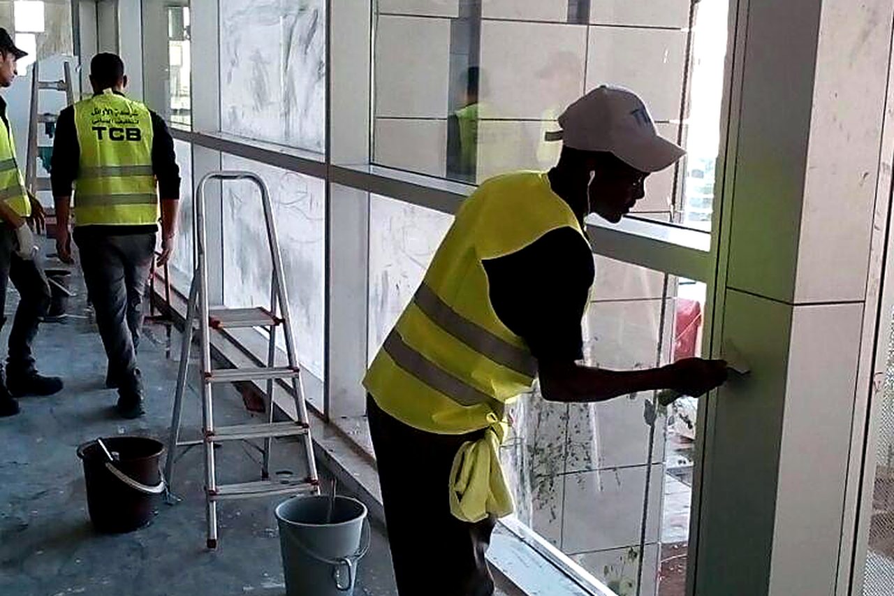 عامل ينظف واجهة زجاجية داخل مبنى قيد الإنشاء